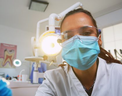 Patient pov visiting dental clinic for surgery treating affected mass. Doctor and nurse working together in modern orthodontic office, lighting the lamp and examining person wearing protection mask.